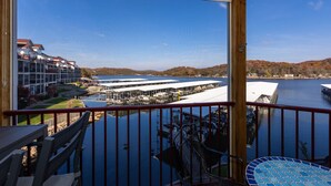 A balcony with a view of a marina and buildings across the water. - Amazing view from water-front condo! Close to golf courses and great dining. (Camdenton)