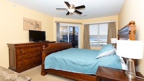 A hotel room with a bed, a wooden dresser, a television, a ceiling fan, a window with curtains, and a view of the city. - Amazing view from water-front condo! Close to golf courses and great dining. (Camdenton)