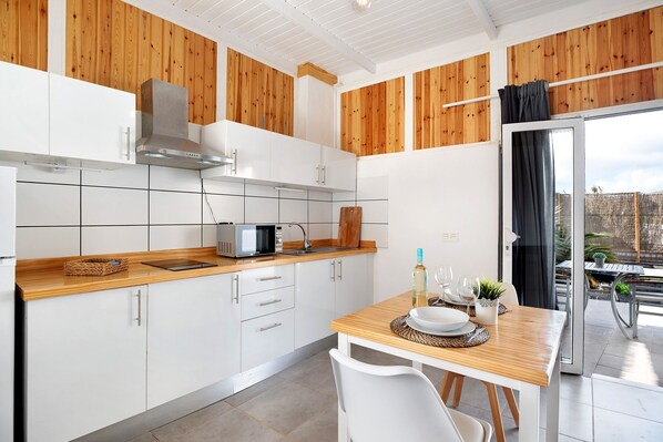 Eine moderne Küche mit weißen Schränken, einer Holz Arbeitsplatte und einem Essbereich mit Tisch und Stühlen.