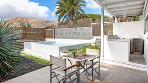 Un patio con piscina, mobiliario exterior y zona de cocina.