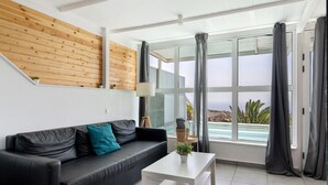 Una sala de estar moderna con un sofá de cuero negro, una mesa de centro blanca y una pared de listones de madera.