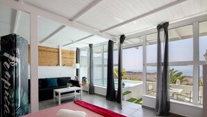 Una habitación de hotel moderna con una cama, un sofá, una mesita y vistas a la playa.