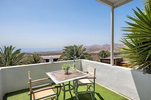 A balcony with a table, chairs, and a potted plant. - Holiday Home 'Loft Amanecer' with Sea Views, Wi-Fi and Air Conditioning (Macher)