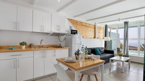 Una cocina moderna con armarios blancos, encimera de madera y un comedor con mesa y sillas.