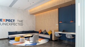 Un vestíbulo moderno con un sofá modular, una zona de bar y un área de estar con otomanas y sillas.