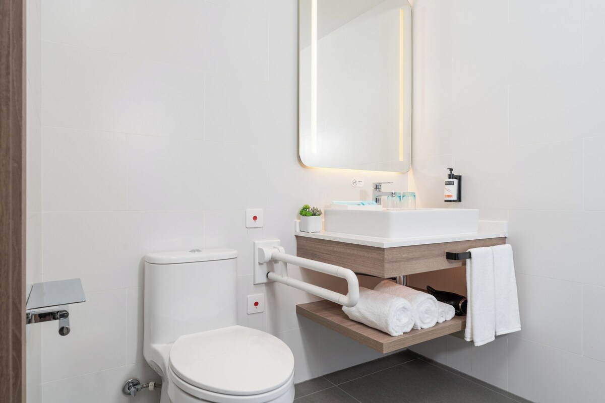 A modern bathroom with a toilet, sink, and mirror.