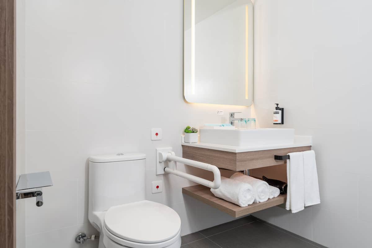 A modern bathroom with a toilet, sink, and mirror.