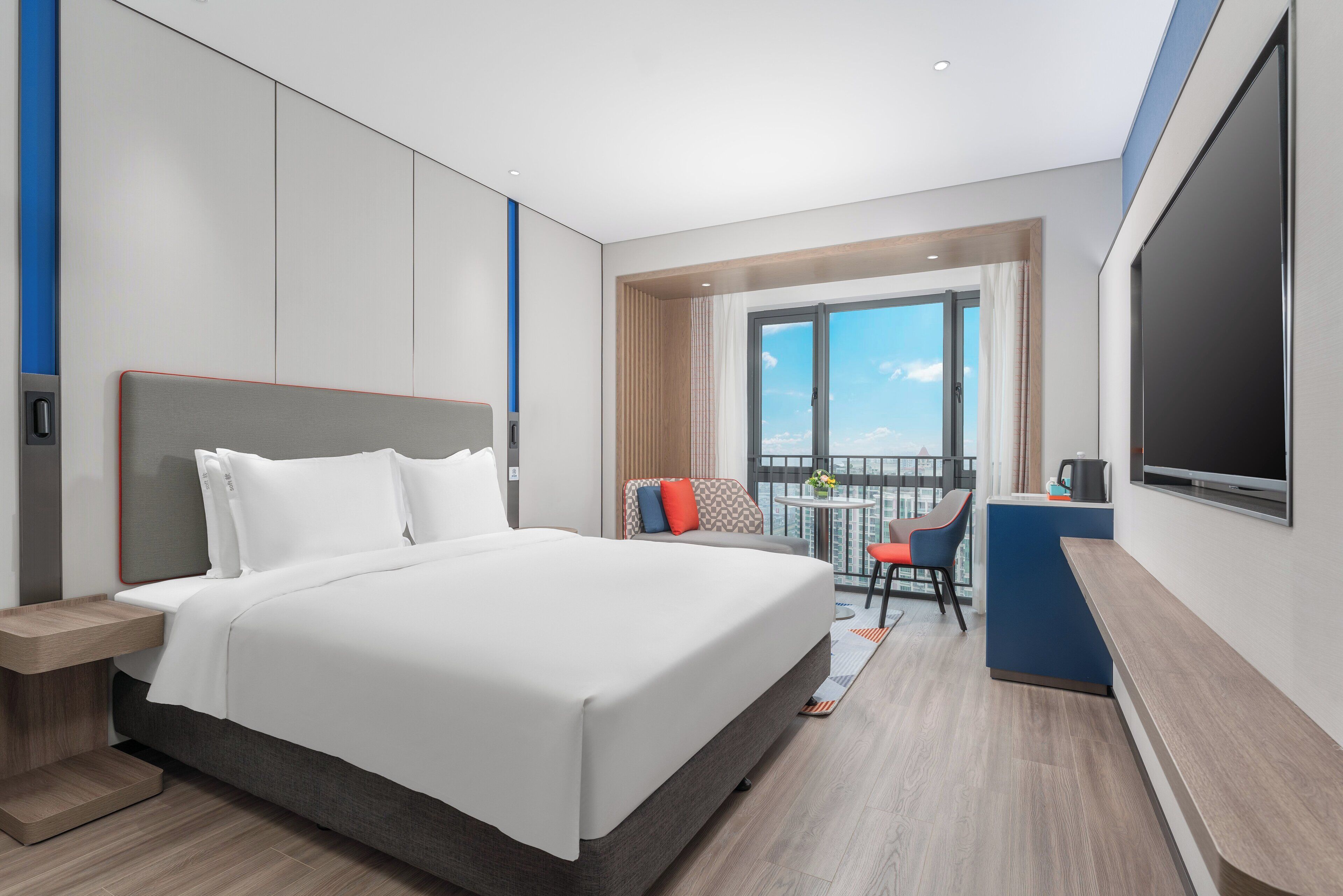 Una habitación de hotel moderna con una cama grande, un escritorio, una silla y un televisor.