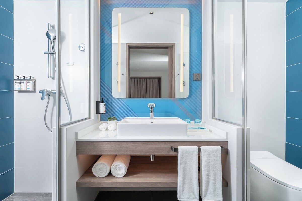 A modern bathroom with a glass shower enclosure, a white sink with a mirror above it, and a toilet.