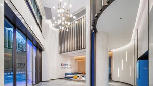 Un vestíbulo moderno con una zona de estar, una lámpara de araña grande y un refrigerador azul.