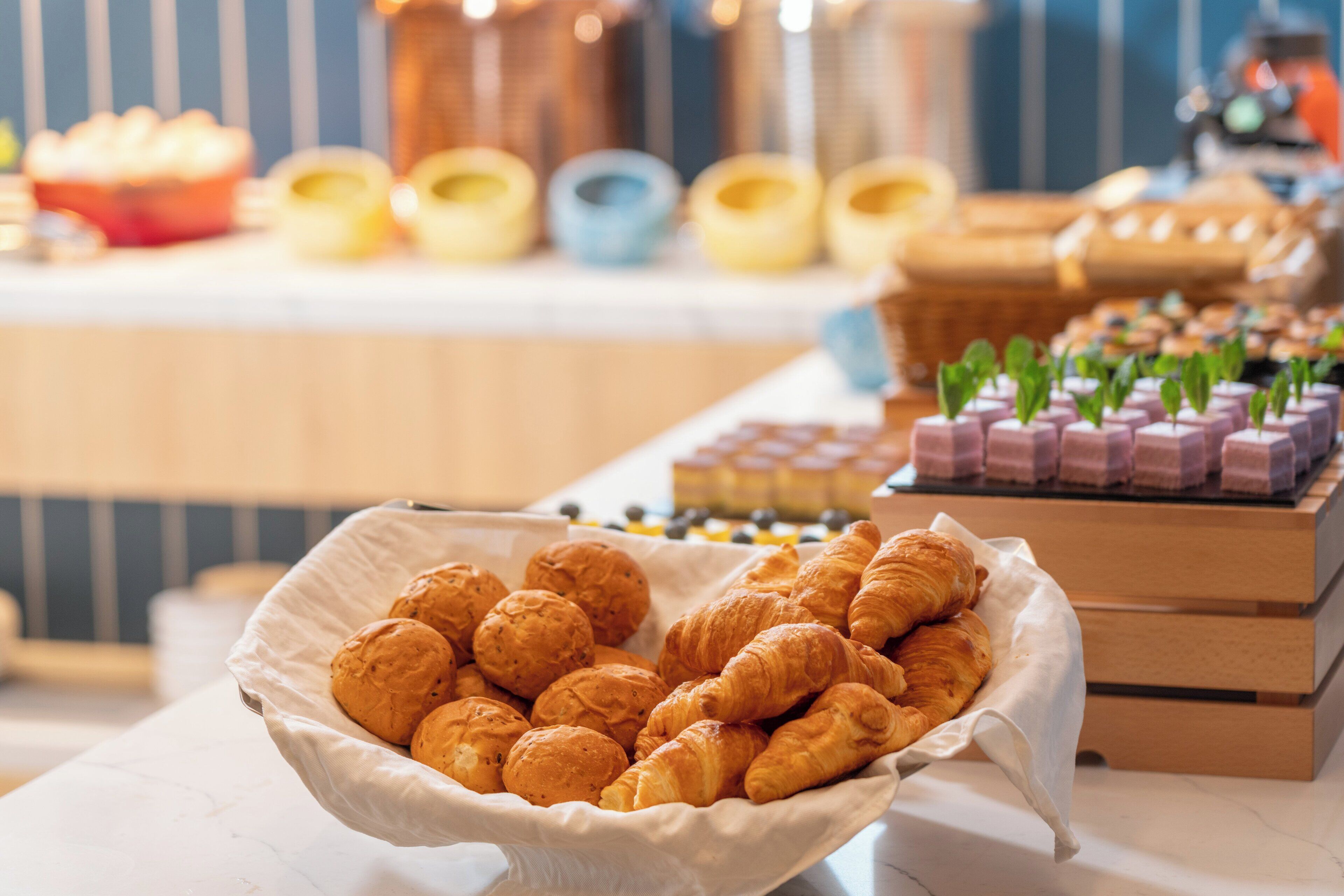 A buffet table with various baked goods, including croissants and pastries, arranged in baskets and containers.