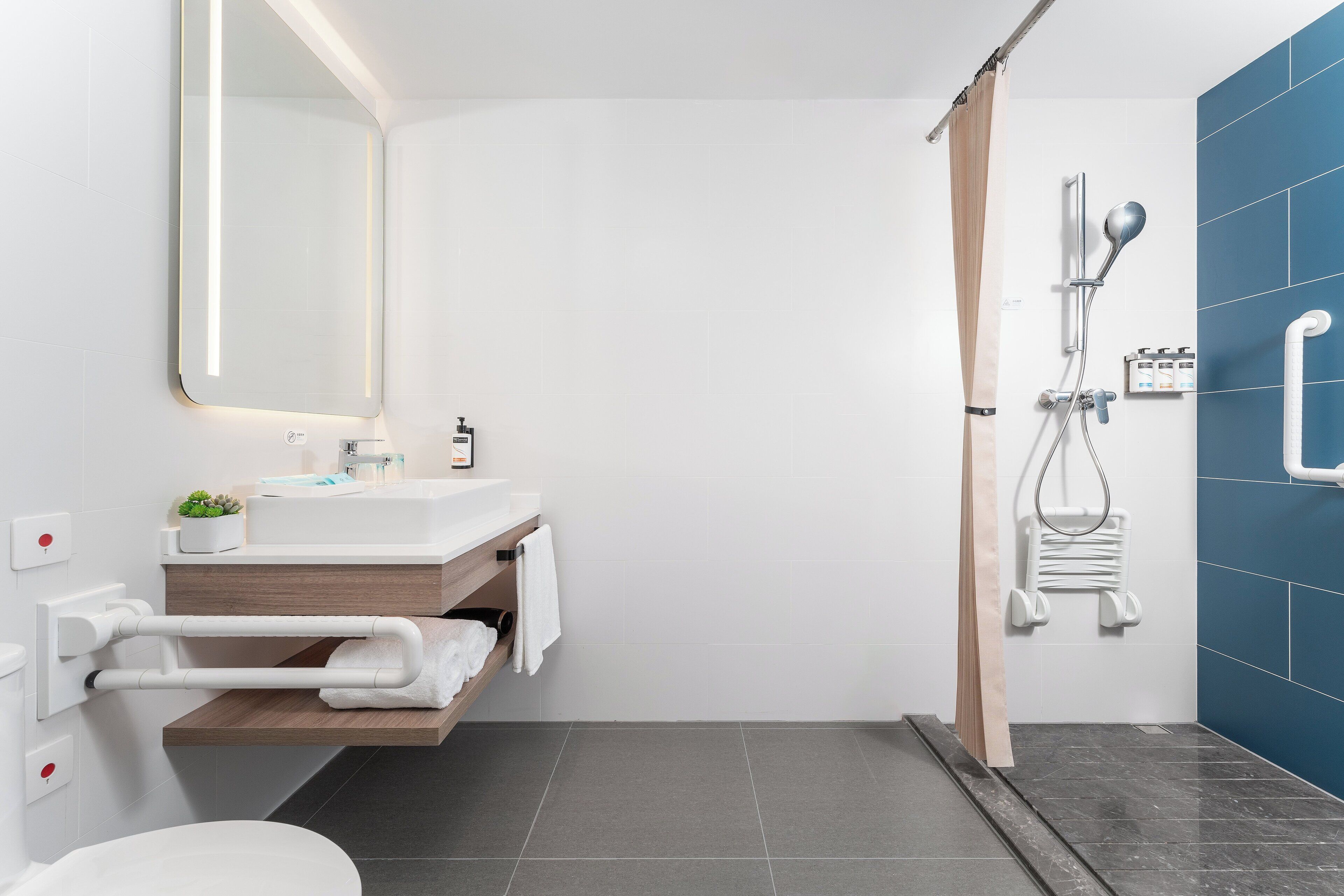 Un baño moderno con lavabo blanco, espejo y ducha.