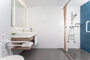 A modern bathroom with a white sink, mirror, and shower.
