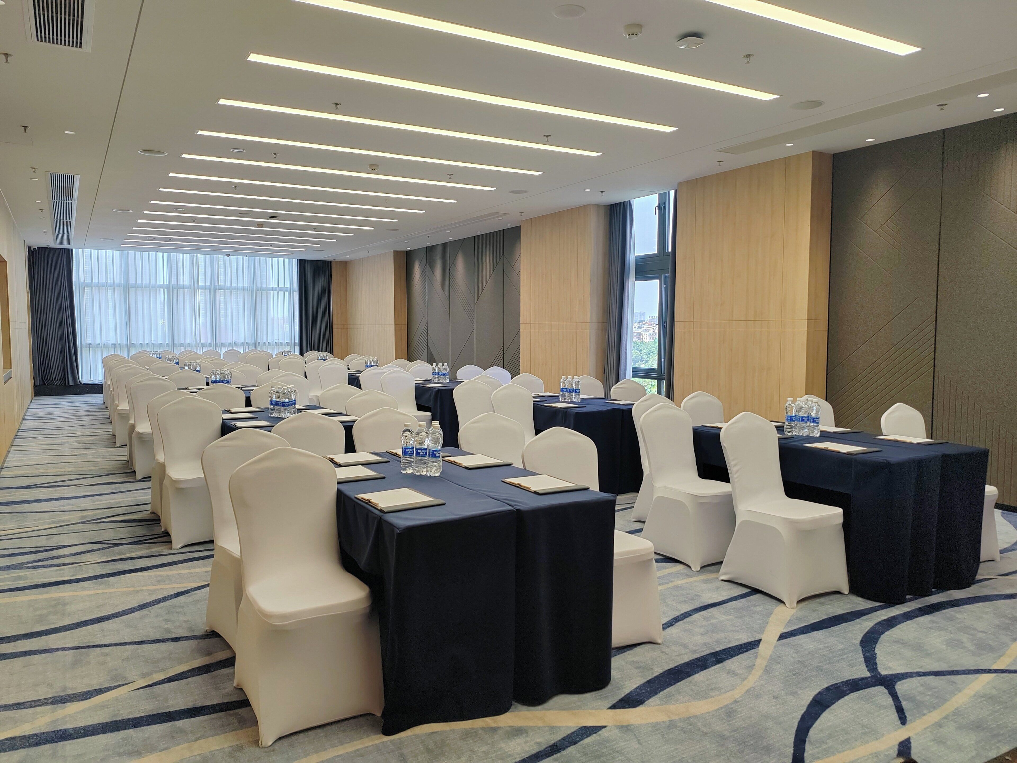 A conference room with rows of tables and chairs, equipped with water bottles and nameplates.