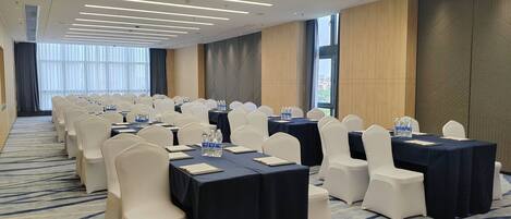 A conference room with rows of tables and chairs, equipped with water bottles and nameplates.