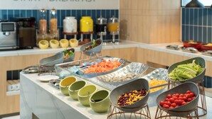 Preparación de un desayuno tipo buffet con diversos alimentos y bebidas.