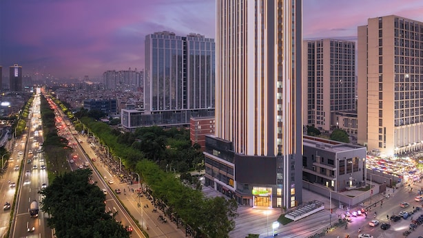Un edificio alto con detalles de iluminación vertical y un letrero llamativo en la parte superior.