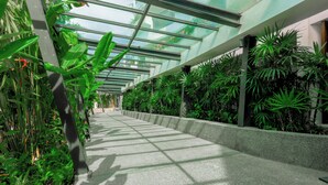 A corridor with a glass ceiling, surrounded by lush green plants. - Holiday Inn Resort Phuket Karon Beach by IHG (Karon)