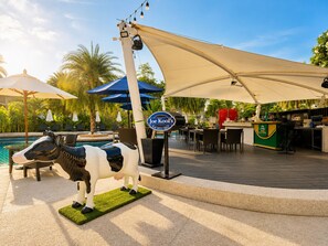 A poolside area with a Joe Kool's Bar-Pizza Grill, outdoor seating, and a decorative cow statue. - Holiday Inn Resort Phuket Karon Beach by IHG (Karon)