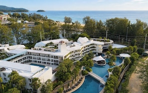 A resort with multiple buildings, a central pool, and a view of the ocean.