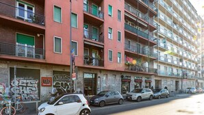 Een meerlaags woongebouw met balkons, een fiets geparkeerd buiten en meerdere auto's langs de straat.