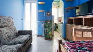 Een kamer met een slaapgedeelte, een bed, een televisie en een keukenhoek.