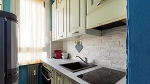 Een keuken met een inbouwfornuis, een spoelbak en een raam met zonwering.