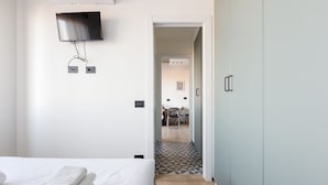 Une chambre d’hôtel avec un lit, un téléviseur fixé au mur et une armoire.