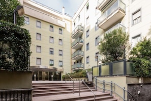 Un edificio de varios pisos con una escalera central, balcones y vegetación.