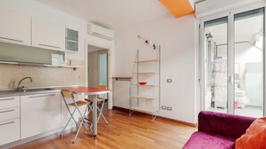 A modern kitchen with white cabinets, a wooden countertop, and a dining area with a red table and chairs.