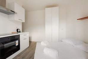 A modern hotel room with a kitchenette, a bed with white linens, and a large wardrobe. - GuestHost - Functional and modern 19 sqm studio, ideal for 2 people, located on the fourth floor of a building without lift. The accommodation is situated few steps away from the Maciachini MM, in a dynamic and well-serviced neighborhood of Milan. Perfec (Milano)