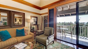 Un salón acogedor con sofá, sillón y mesa de centro, un balcón con mobiliario exterior y un gran ventanal.