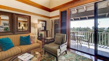 A cozy living room with a sofa, armchair, and coffee table, a balcony with outdoor furniture, and a large window.