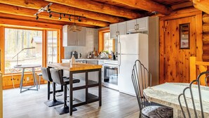 L’intérieur d’un chalet en bois comprend une cuisine, un coin repas et de grandes fenêtres.