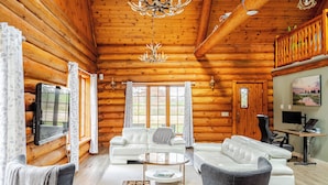 L’intérieur d’une cabane en rondins comprend un salon, un canapé, une table basse et un téléviseur.