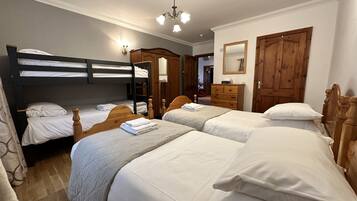 Un dormitorio con literas, un aparador de madera, un espejo y una araña.