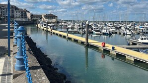 A marina with boats docked, a clear sky, and a stone walkway with blue chains. - Malahide Guest Rooms (Malahide)