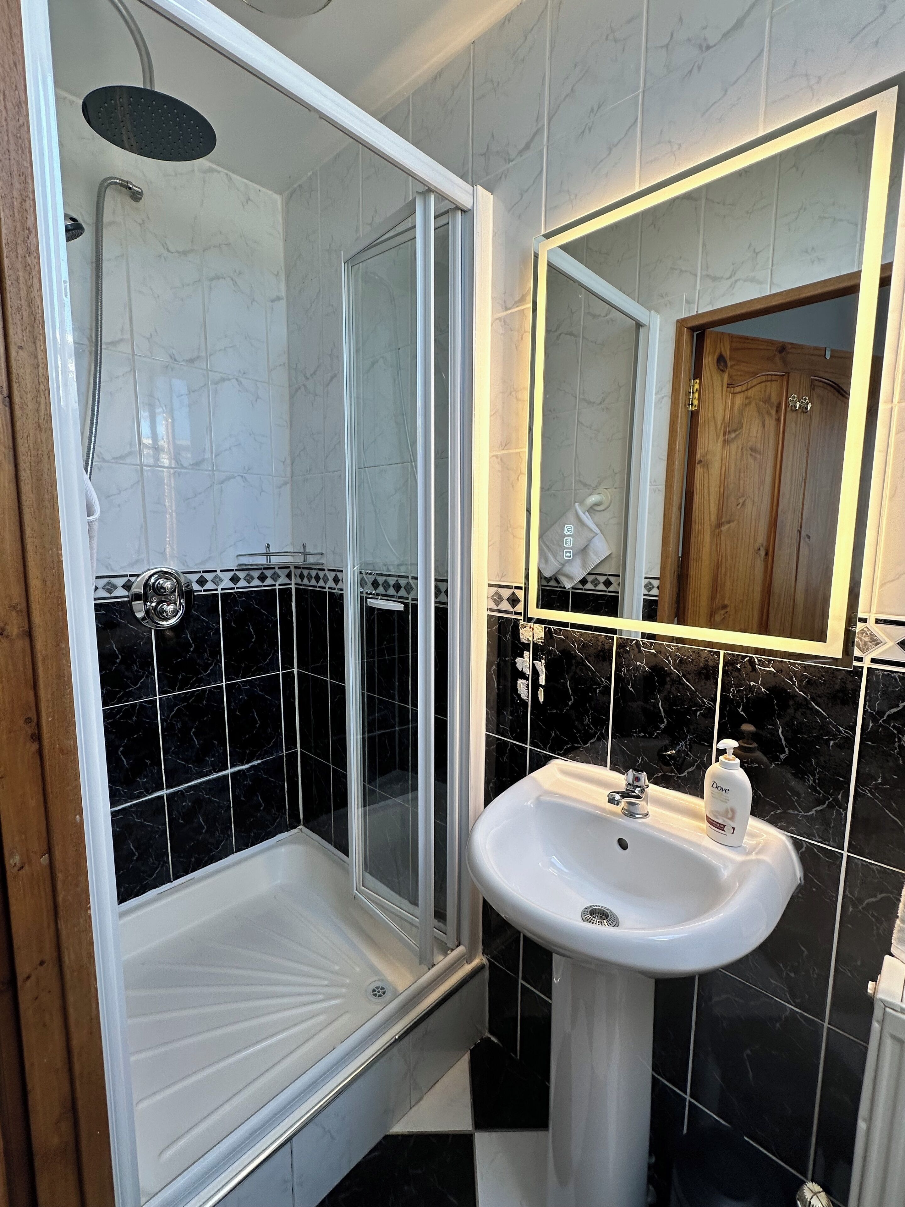 A bathroom with a glass-enclosed shower, a white sink, and a mirror above it.