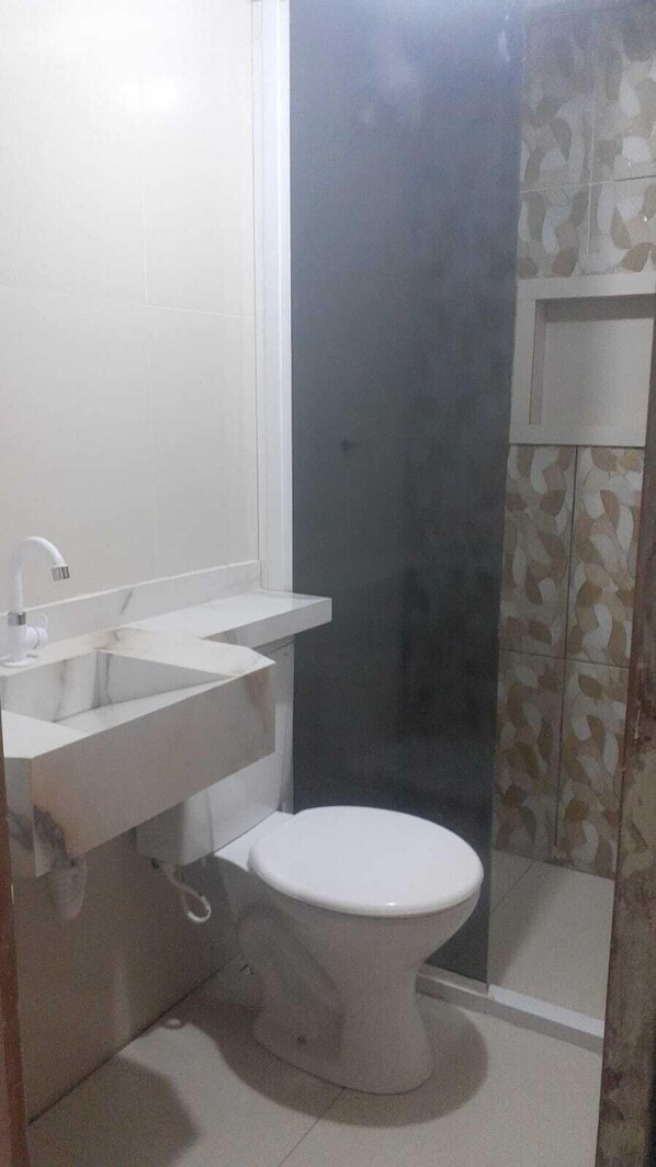 Casa de banho pequena com sanita, lavatório e zona de duche.