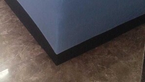 Habitación de hotel con colcha azul, cabecera de madera y un par de toallas enrolladas sobre la cama.