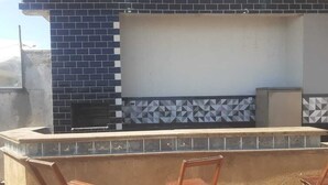 Un patio al aire libre con una parrilla incorporada y asientos.
