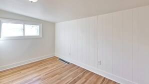 A room with a wooden floor, white walls, a window, and a ceiling light fixture. - 4 Bed, 1.5 Bath East SLC Apt - Blazing Google Fiber (Salt Lake City)