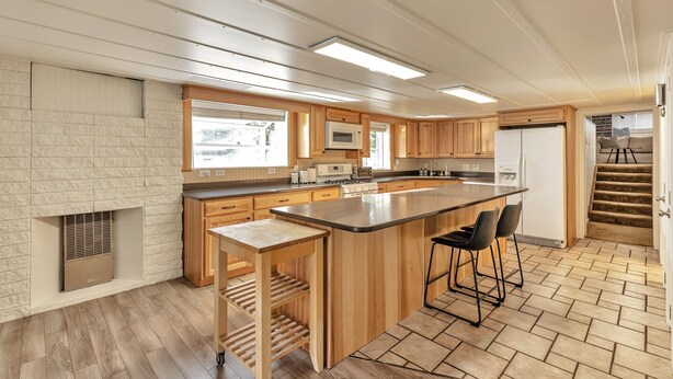 A modern kitchen with wooden cabinets, a central island, and a built-in microwave. - 4 Bed, 1.5 Bath East SLC Apt - Blazing Google Fiber (Salt Lake City)
