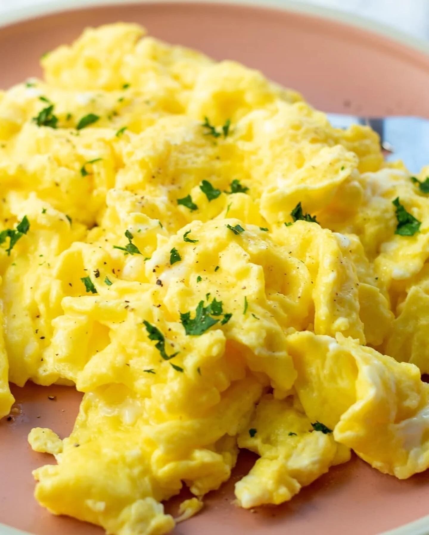 Scrambled eggs garnished with herbs on a plate.