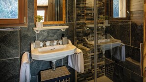 Un baño moderno con cabina de ducha de vidrio, tocador de madera y un espejo grande.