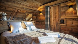 Acogedor dormitorio de cabaña de madera con cama, almohadas, una manta y un soporte para esquíes.