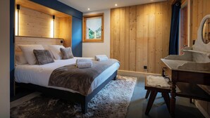 Camera da letto moderna con un ampio letto, rivestimenti in legno, una piccola finestra e una toeletta con specchio.
