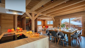 Eine geräumige Küche mit einer Holztischinsel, ein Essbereich mit großem Tisch und Stühlen sowie ein gemütlicher Wohnbereich mit Sofa und Kamin.
