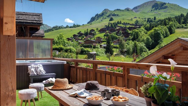 Eine Holzterrasse mit gedecktem Tisch, mit Blick auf eine Berglandschaft.