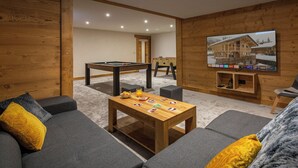 Ein gemütliches Wohnzimmer mit Billardtisch, einer Couch und einem Fernseher.